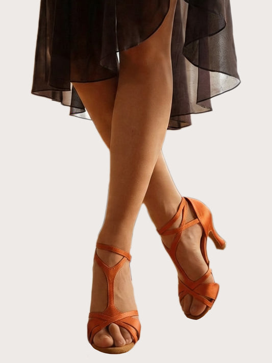 Orange Satin Latein‑Tanzschuhe mit überkreuzten Riemchen und 8‑cm Absatz an Tänzerbeinen vor hellem Hintergrund