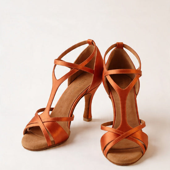 Orange Satin Latein‑Tanzschuhe mit überkreuzten Riemchen und 8‑cm Absatz an Tänzerbeinen vor hellem Hintergrund